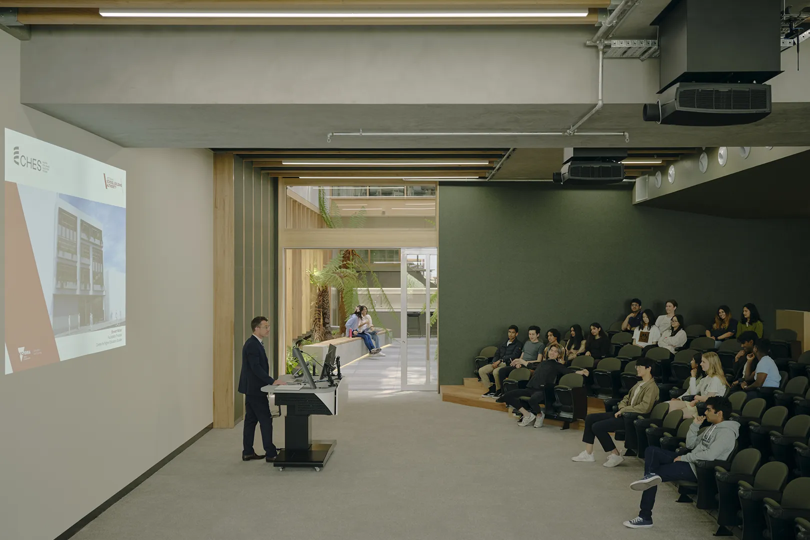 Lecture theatre with tiered seating, presentation facilities, and views to a landscaped courtyard.