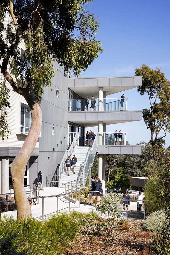 Students using outdoor stairs, walkways, and terraces surrounded by landscaped gardens and mature trees.