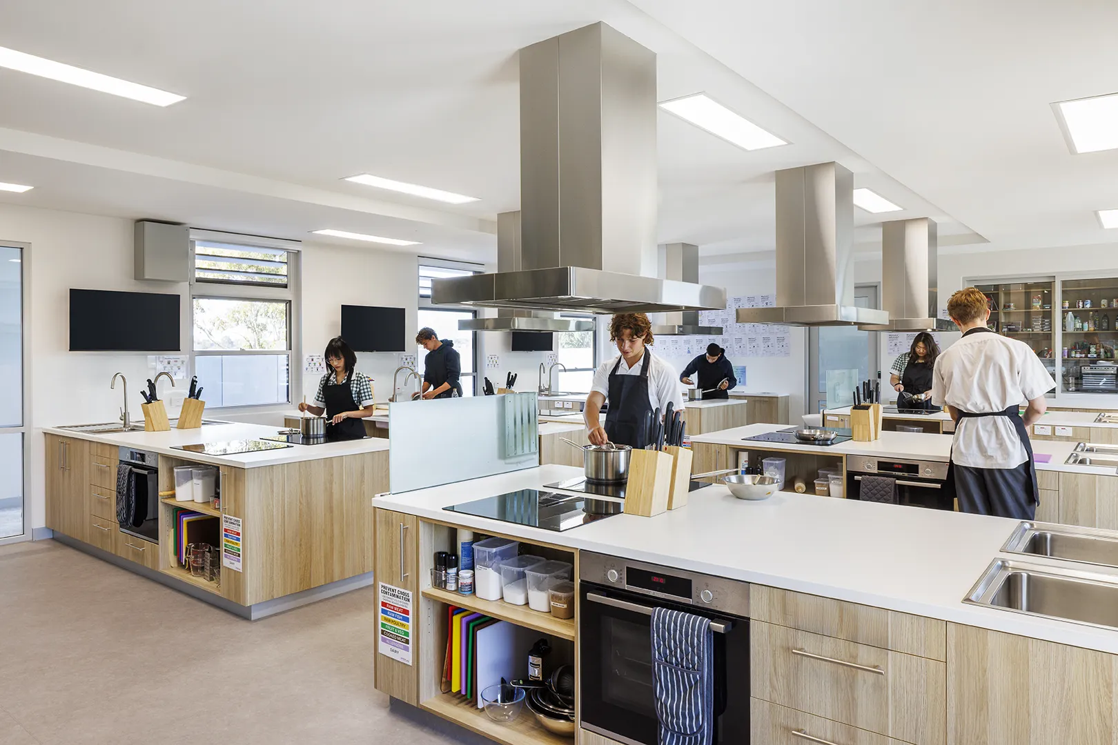 Students using a food technology classroom with cooking stations, appliances, and practical learning areas.
