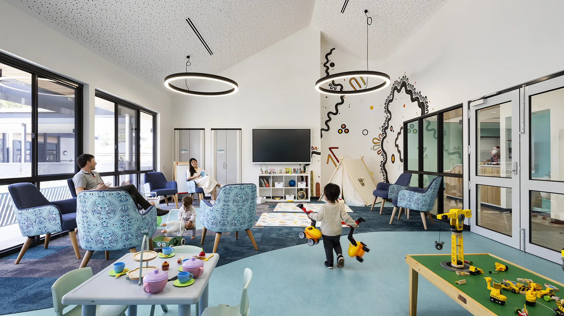 Family play and activity room with children's toys, comfortable seating, and spaces for parents and young children to spend time together.