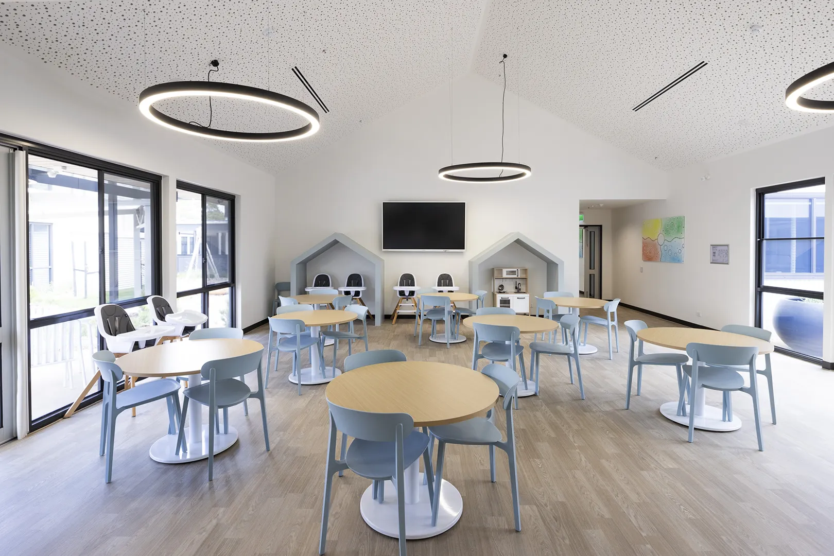 Multipurpose dining and activity space with tables, high chairs, and facilities for family meals and group programs.