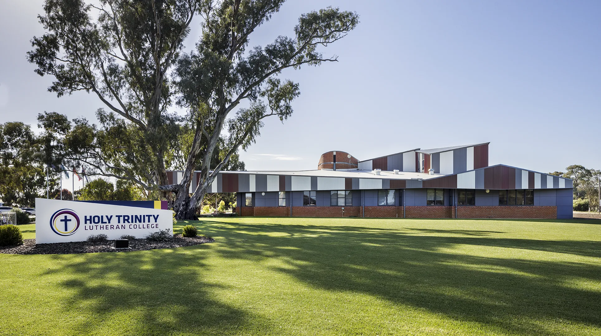 School campus building set within open green spaces, mature trees, and landscaped grounds.