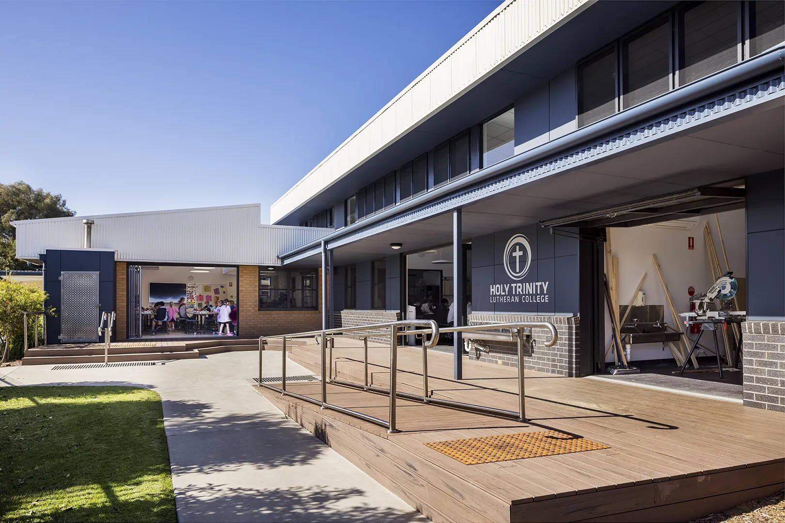 School building with covered walkways, accessible entry ramps, and flexible indoor learning spaces opening to outdoor areas.