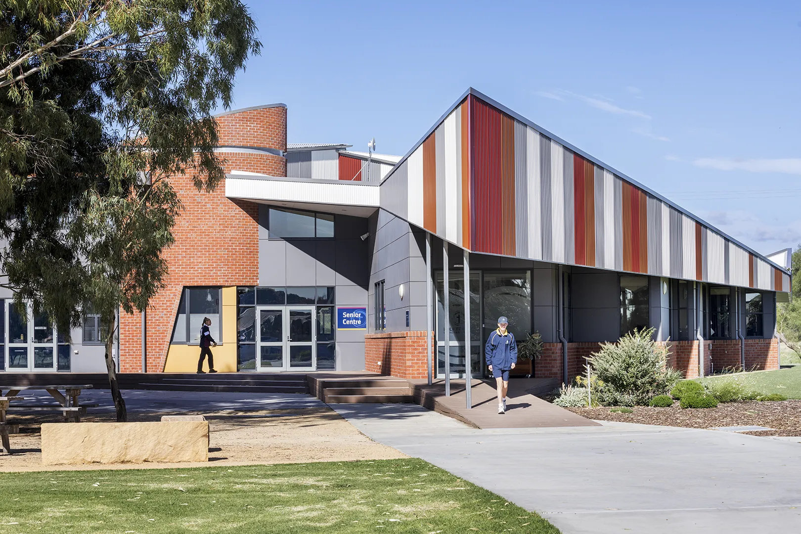 Education building with a distinctive roofline, landscaped grounds, and pathways connecting indoor and outdoor learning spaces.