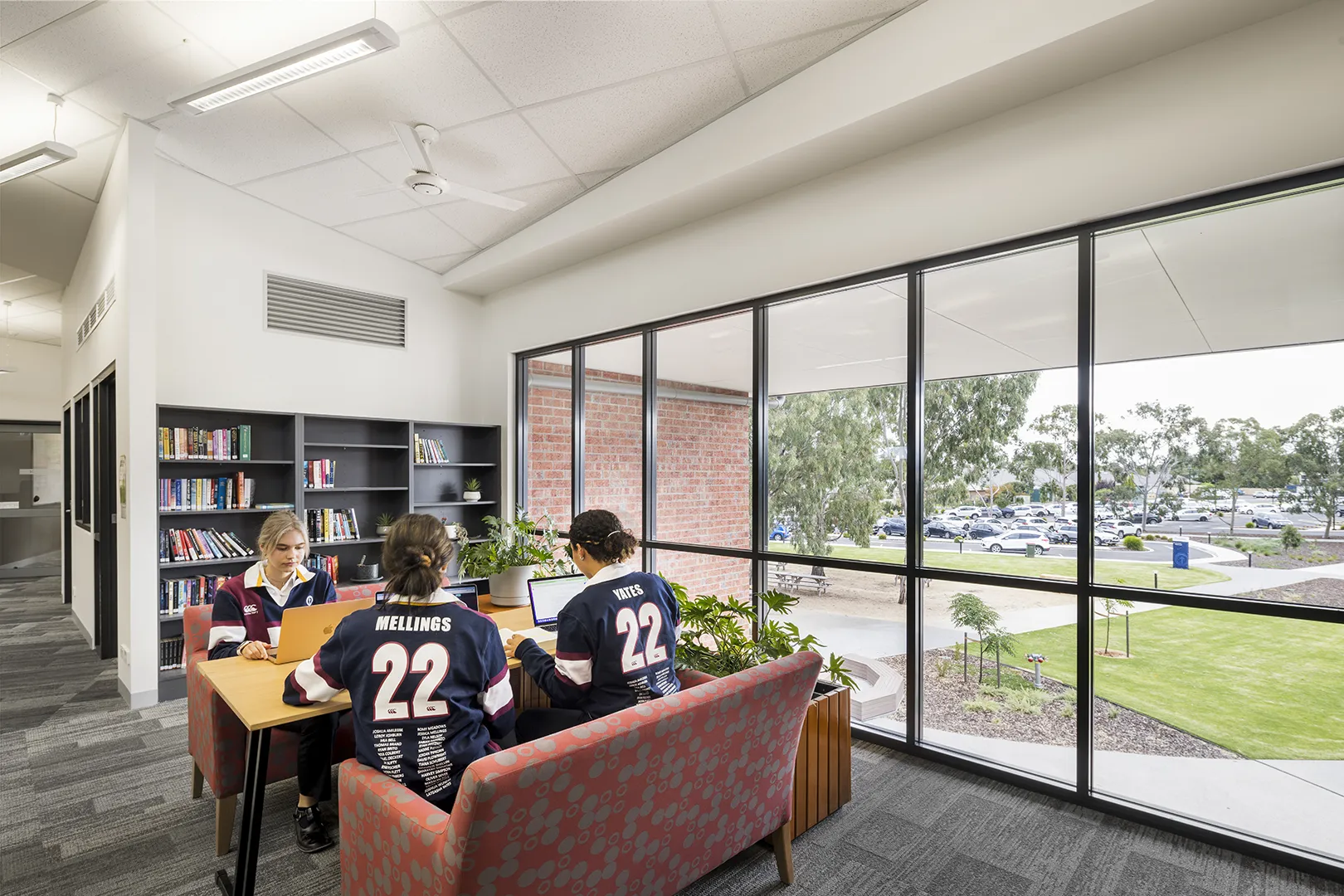 Students studying together in a shared learning area with comfortable seating and large windows overlooking the campus.