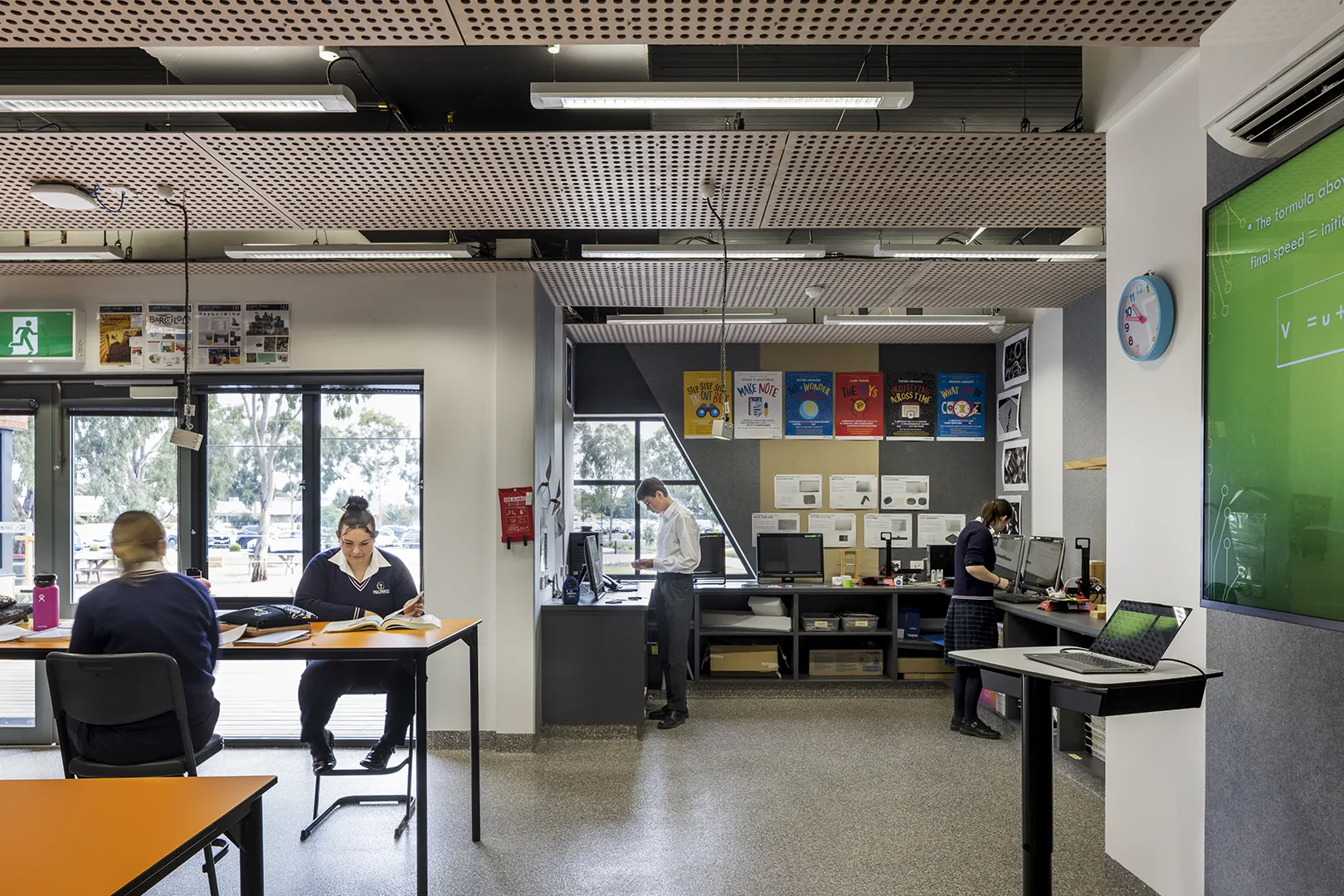 Students working in a classroom with computers, study tables, and spaces for individual and group learning.