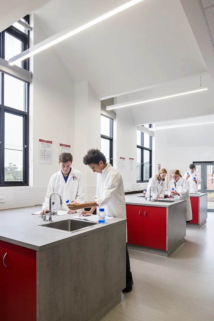 Students carrying out science experiments in a laboratory with practical workstations and large windows providing natural light.