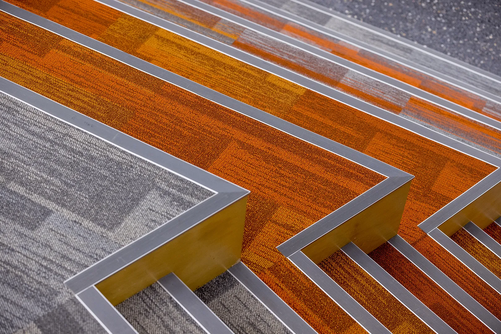 Close-up of tiered seating with orange and grey finishes used for informal learning and gathering.