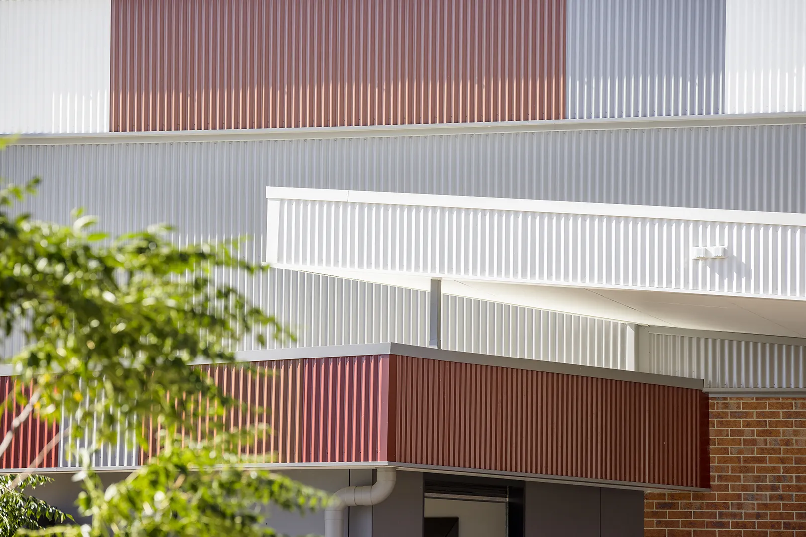 Exterior building detail featuring coloured wall panels, covered walkways, and layered façade elements.