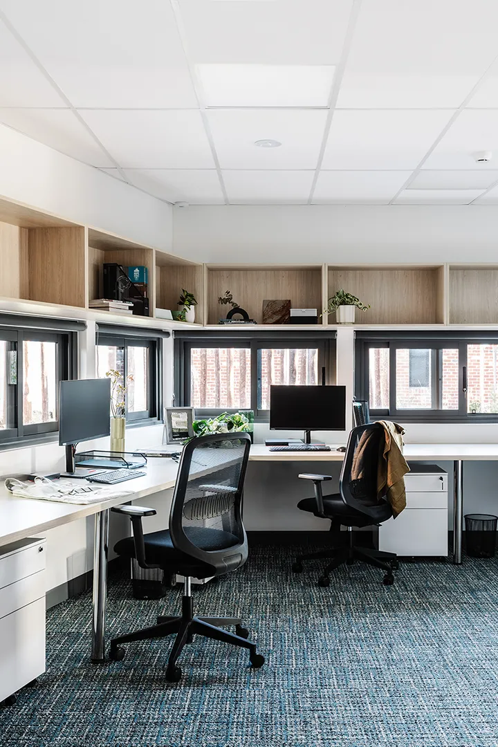 Office workspace with desks, computers, and natural light supporting staff and support services.