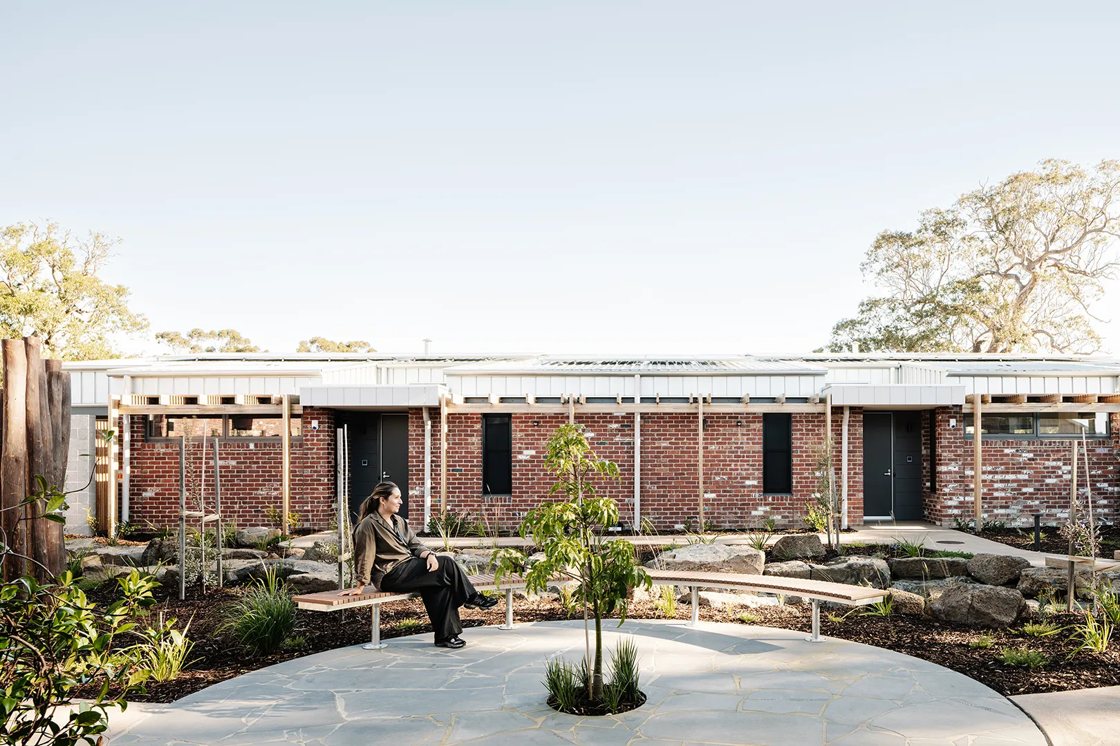 Landscaped courtyard with outdoor seating, garden planting, and private accommodation arranged around a shared open space.