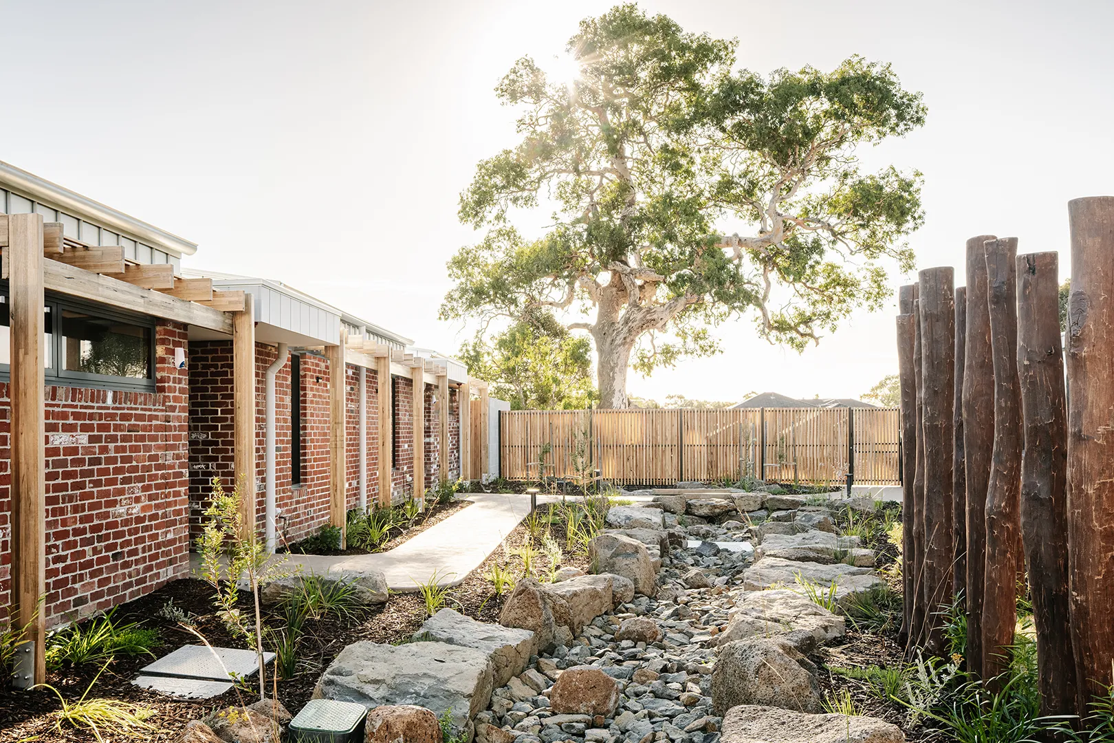 Landscaped outdoor area with walking paths, garden planting, and shared open spaces surrounding the accommodation buildings.