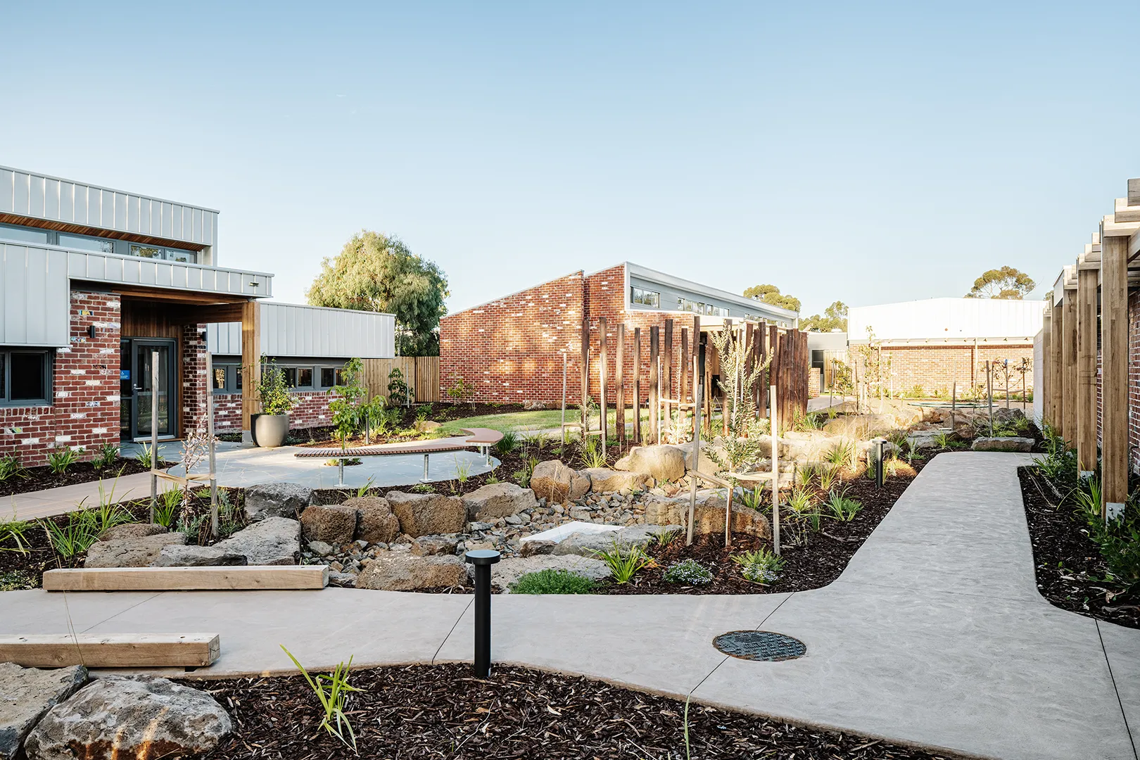 Shared courtyard with landscaped gardens, seating, walking paths, and accommodation buildings arranged around a central open space.