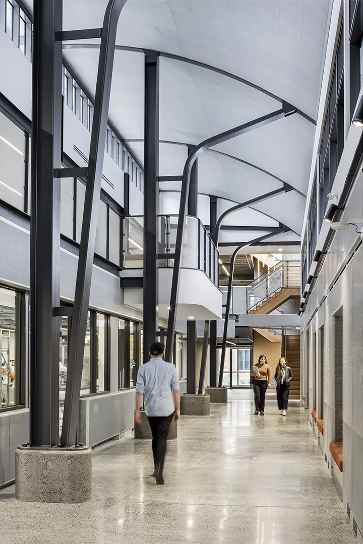 Open internal walkway with high ceilings, shared circulation spaces, and people moving through the building.