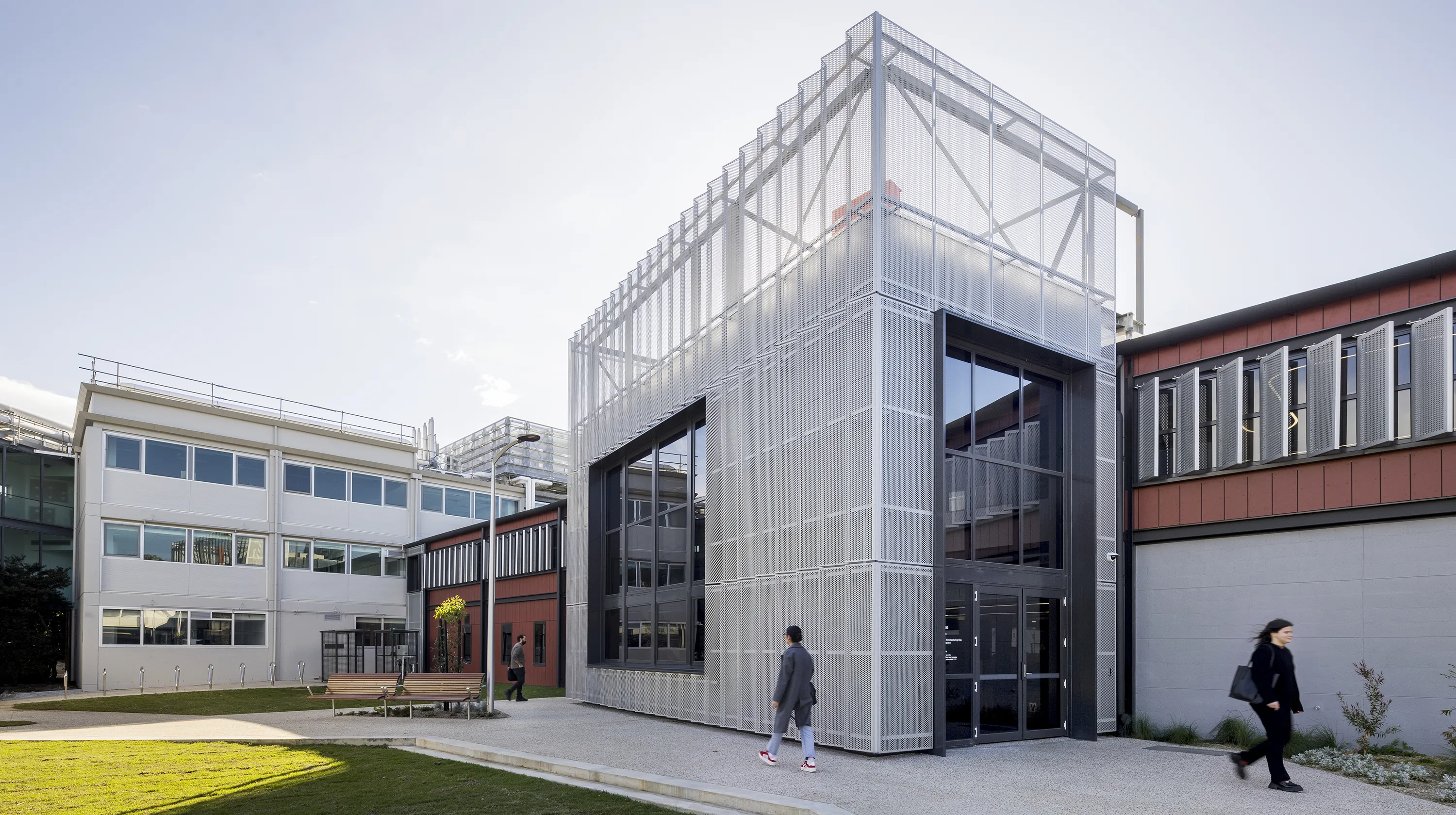 Monash Innovations Lab Clayton building with a central courtyard, outdoor seating, and people moving between connected learning and research spaces.