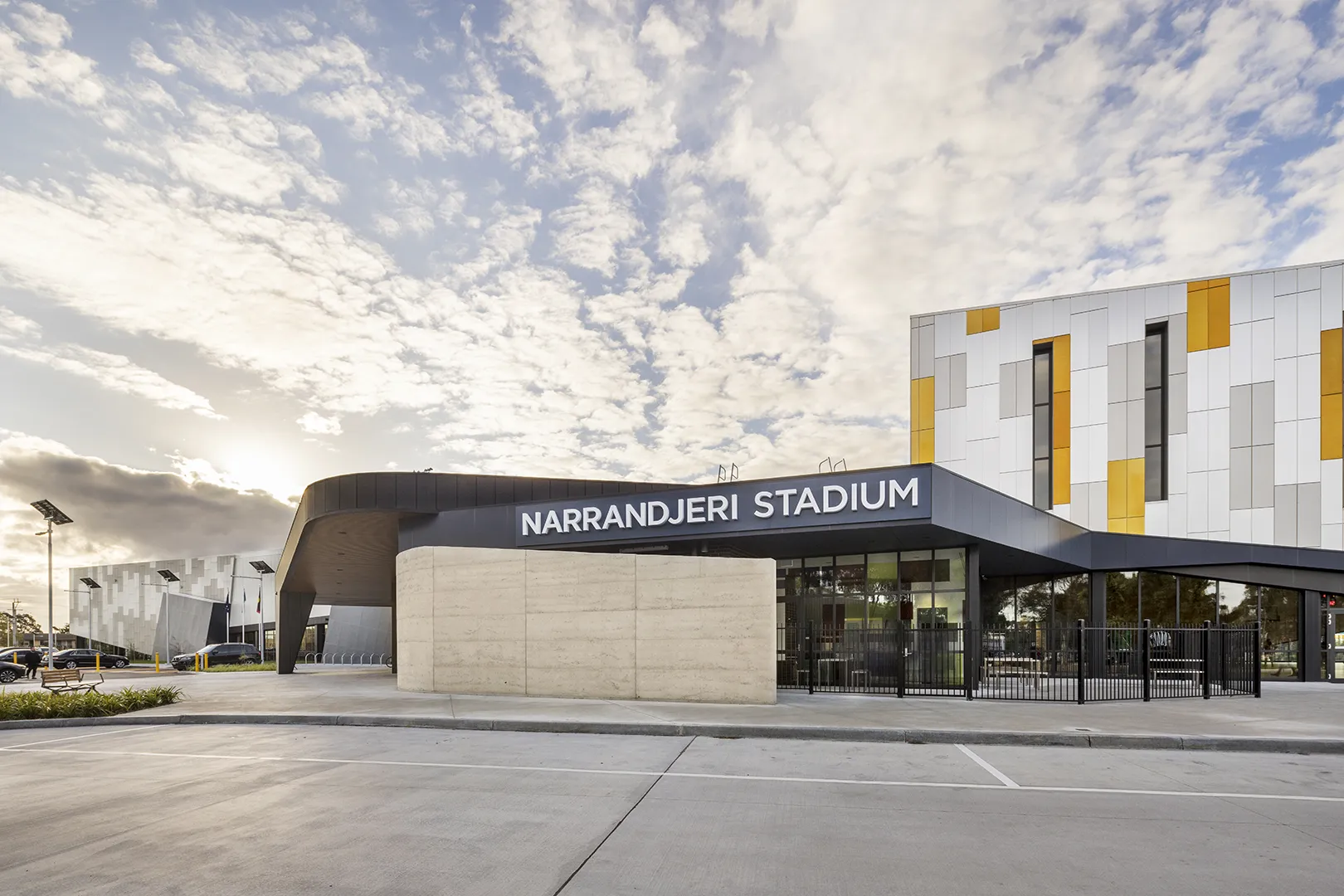 Stadium entrance featuring clear visitor access, outdoor gathering areas, and landscaped surrounds.