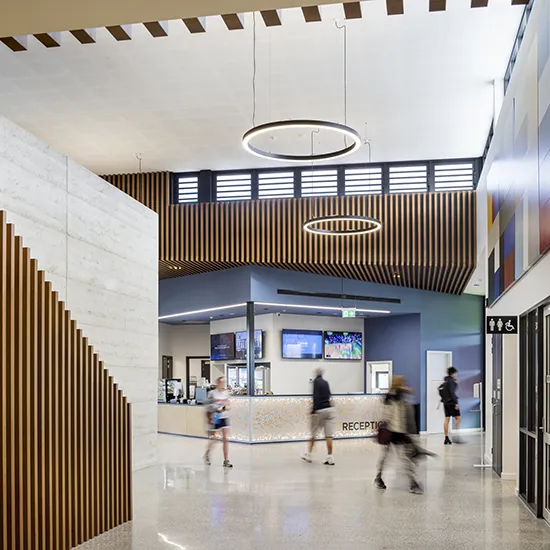 Visitors moving through the stadium foyer with reception services, seating areas, and access to community facilities.