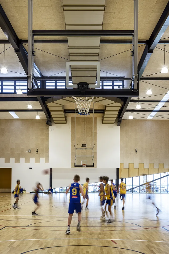 Players participating in a basketball game inside a multi-purpose indoor sports court.