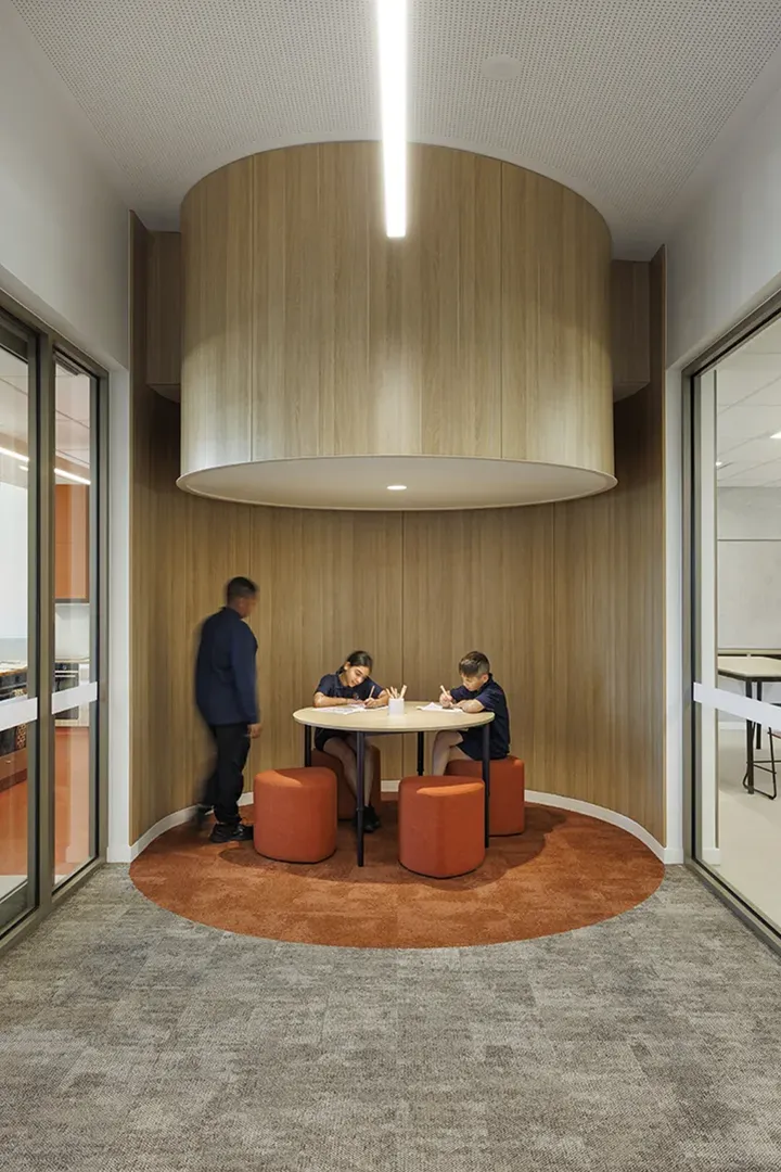 Small study area with a round table, soft seating, and timber finishes for quiet learning and collaboration.