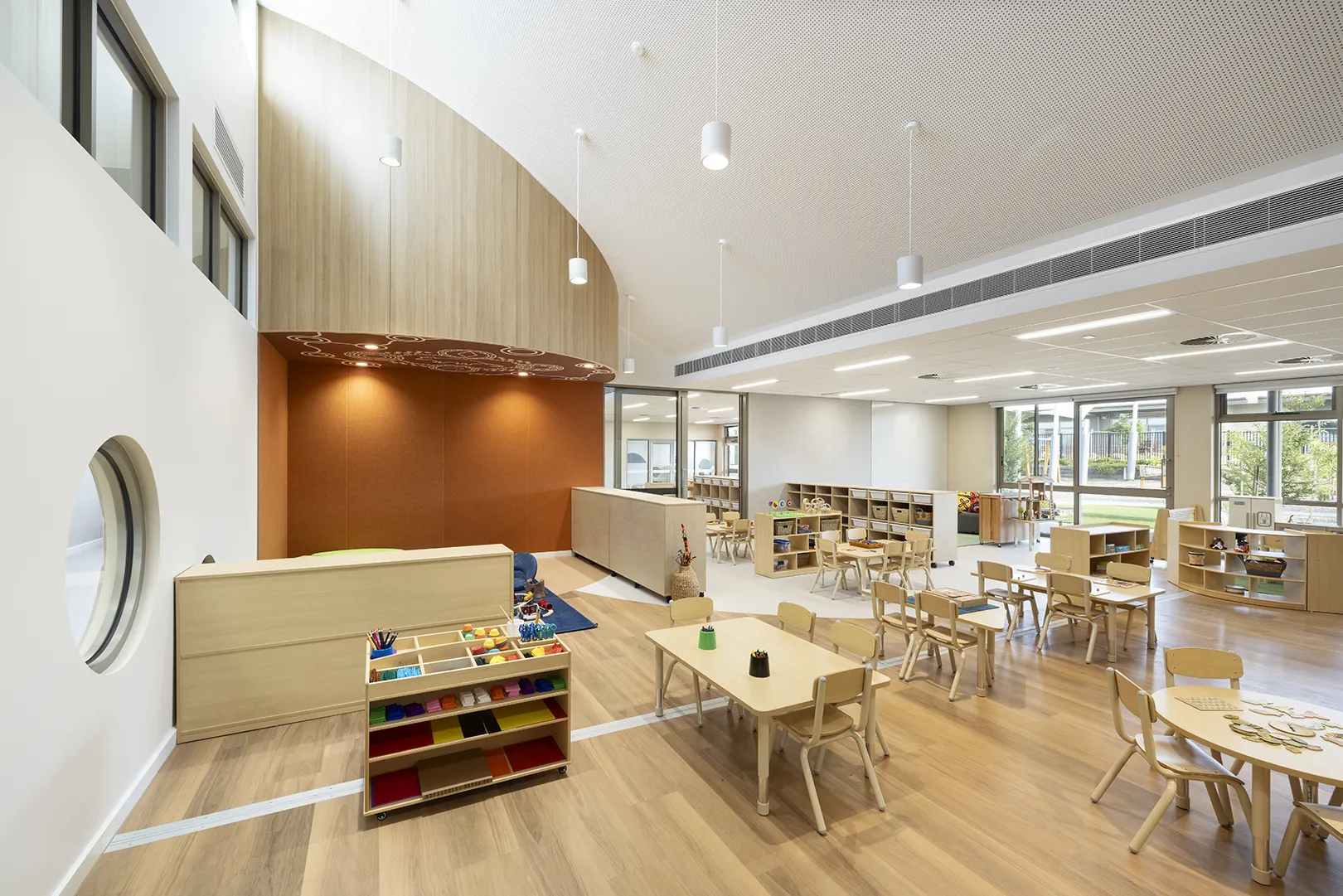 Early learning classroom with flexible activity areas, child-sized furniture, and large windows overlooking outdoor spaces.