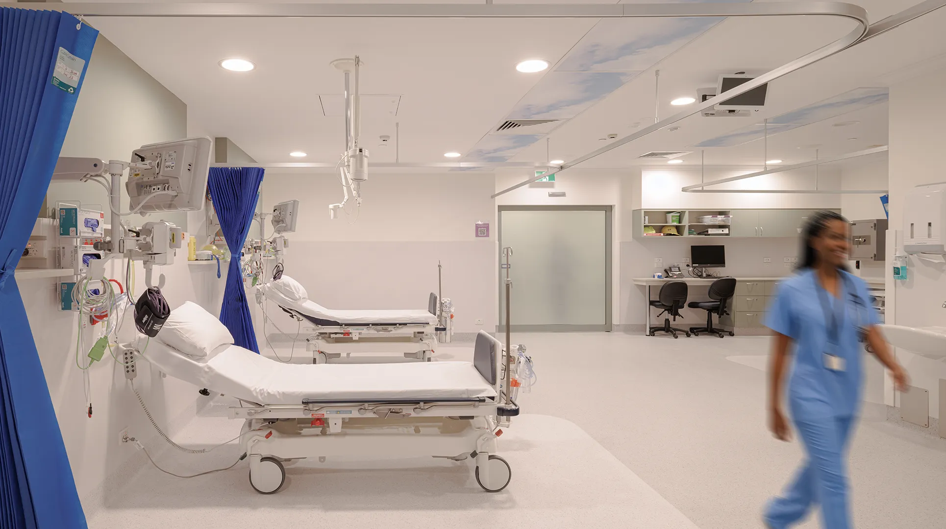 Open recovery ward with patient bays, integrated monitoring equipment, and adjacent clinical workstations supporting efficient care delivery.
