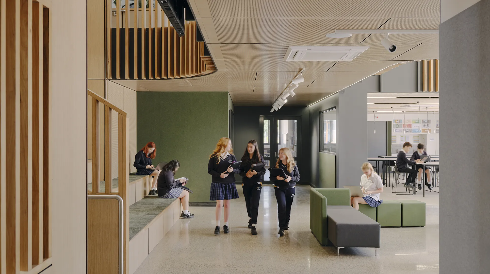 Students collaborating and studying in a shared learning space with informal seating, breakout areas, and natural light.