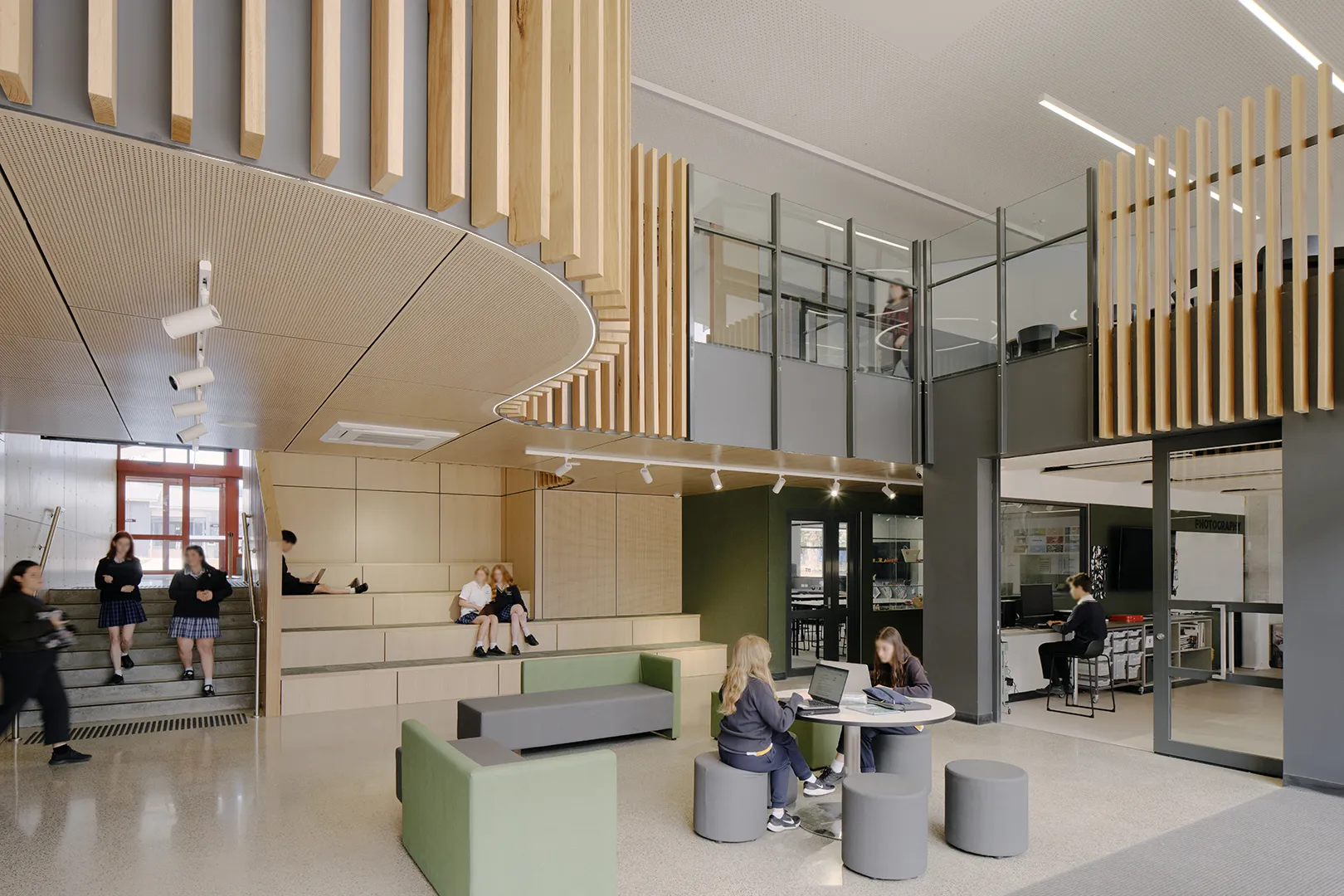 Students collaborating in an open learning hub with flexible seating, study areas, and connected classroom spaces.