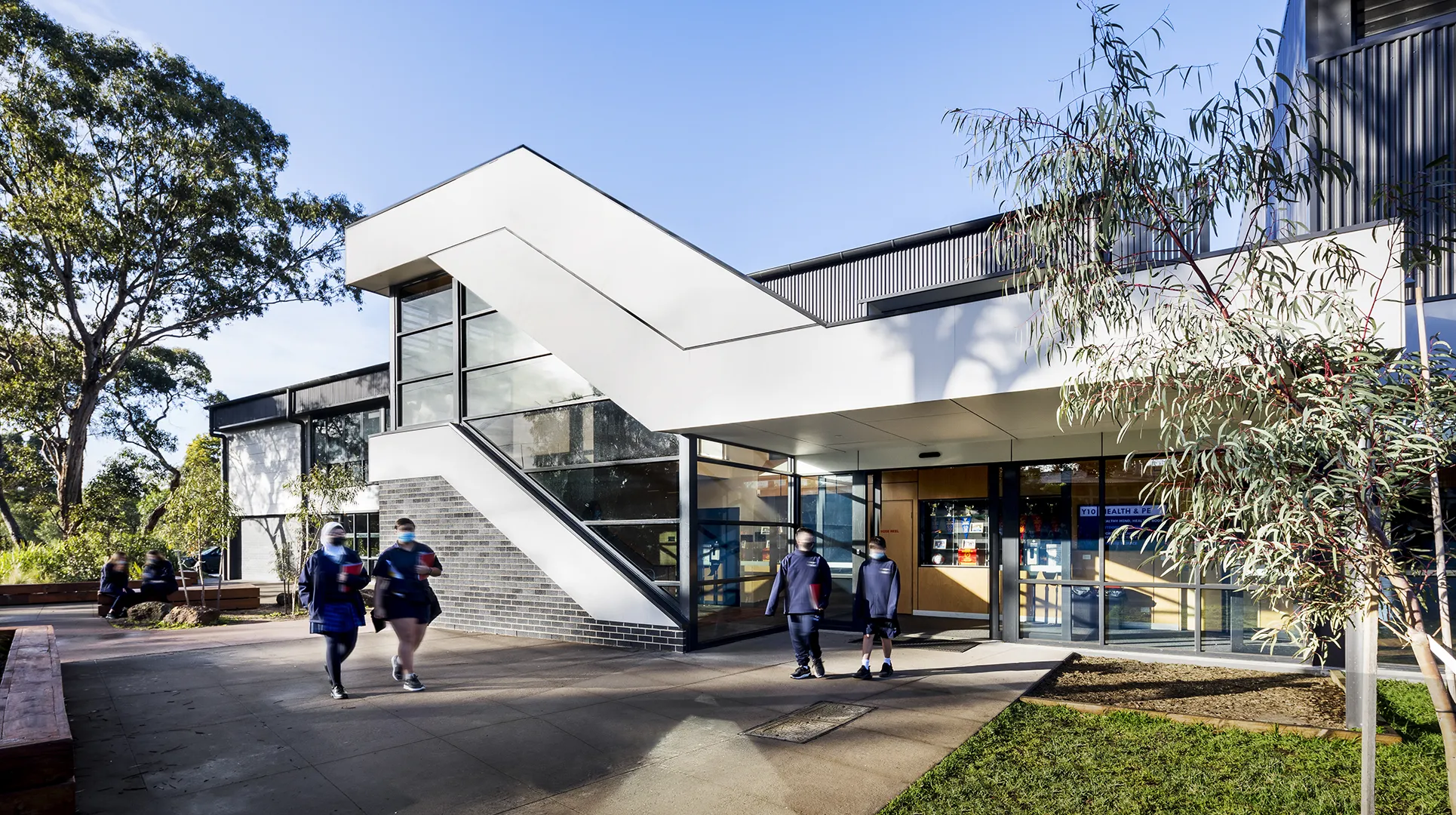 Students arriving at the sports and performing arts centre through landscaped outdoor areas and covered entrances.